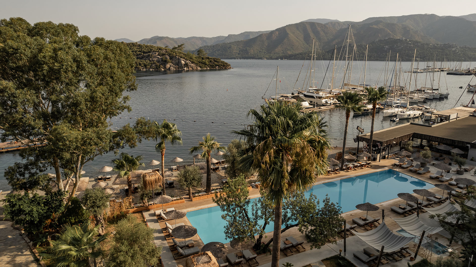 Luxury pool and marina view with mountains, serene coastal hotel destination