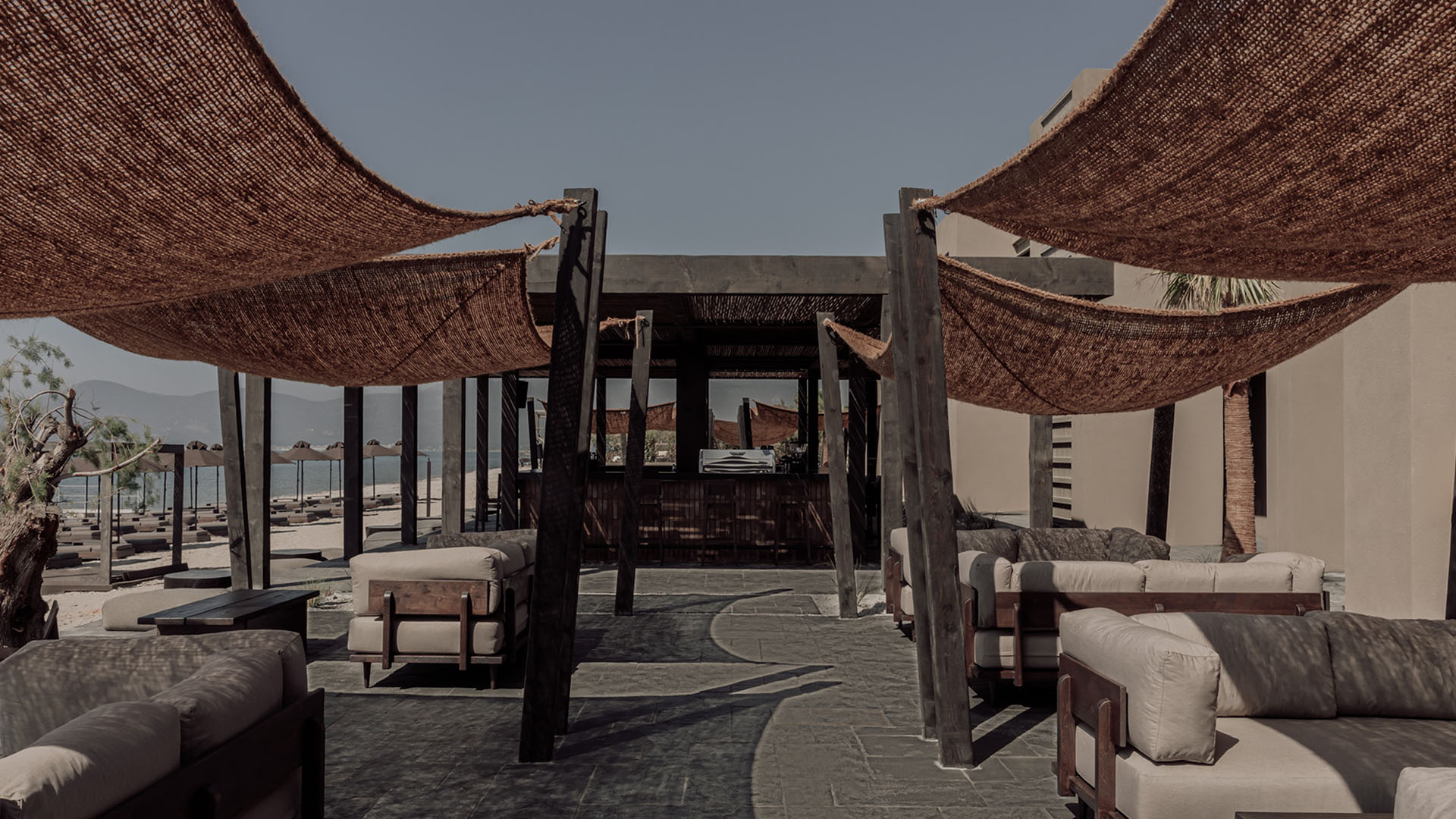 Outdoor hotel lounge with fabric shades and natural materials, comfortable social space
